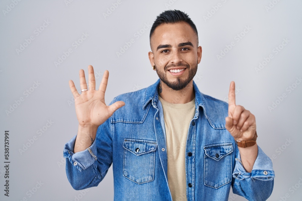 Canvas Prints Young hispanic man standing over isolated background showing and pointing up with fingers number six while smiling confident and happy.