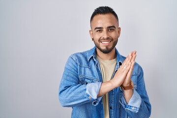 Young hispanic man standing over isolated background clapping and applauding happy and joyful, smiling proud hands together