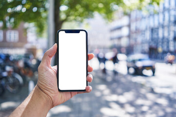 Man holding smartphone showing white blank screen at street