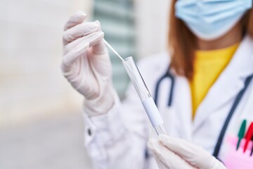 Young caucasian woman doctor wearing medical mask holding pcr test at hospital
