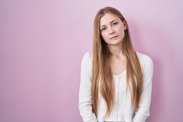Fototapeta premium Young caucasian woman standing over pink background looking sleepy and tired, exhausted for fatigue and hangover, lazy eyes in the morning.