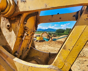 Peering Through Arm of Excavator with Excavator in Background and Screeners