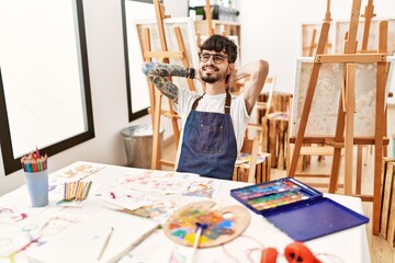 Young hispanic artist man relaxed with hands on head at art studio.