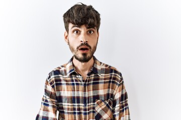 Hispanic man with beard standing over isolated background afraid and shocked with surprise expression, fear and excited face.