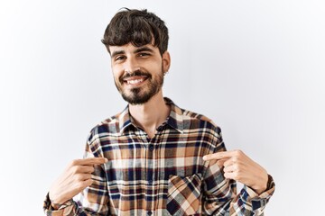 Hispanic man with beard standing over isolated background looking confident with smile on face,...