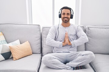 Young hispanic man doing yoga exercise sitting on sofa at home