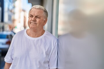 Fototapeta premium Middle age grey-haired man looking to the side with relaxed expression at street