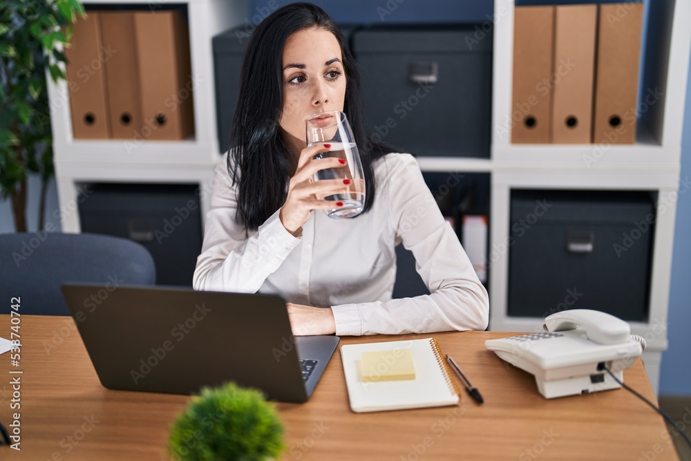 Sticker Young caucasian woman business worker using laptop drinking glass of water at office