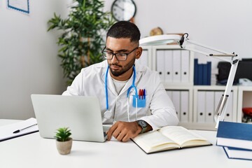 Young arab man wearing doctor uniform reading book at clinic