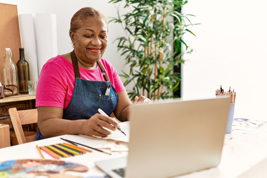Senior african american woman drawing using laptop at art studio