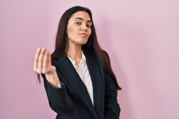 Fototapeta premium Young brunette woman wearing business style over pink background doing italian gesture with hand and fingers confident expression