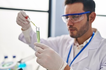 Young hispanic man scientist measuring liquid at laboratory