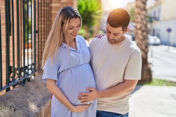 Naklejka premium Man and woman couple hugging each other expecting baby at street