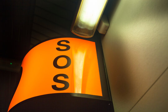 Cartel o panel de emergencia SOS de color naranja bañado por lampara de tubo fluorescente