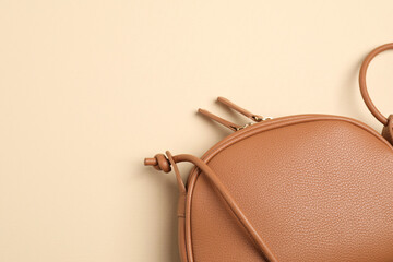 Stylish leather handbag on beige background, closeup. Space for text