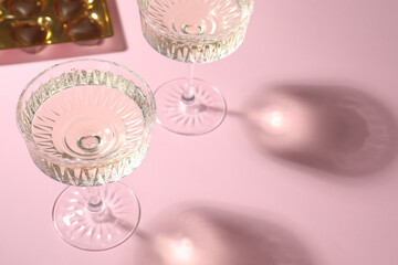 Glasses of expensive white wine on pink background. Space for text
