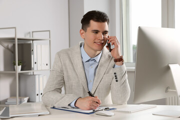 Businessman talking on phone while working in office