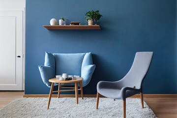 Real photo of a blue, wide chair standing on a rug in a spacious living room interior with grey walls and wooden floor next to a shelf and a table