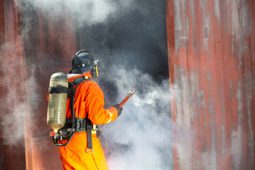 Firefighter on duty firefighting, Asian fireman spraying high pressure water, Fireman in fire fighting equipment uniform spray water from hose for fire fighting.