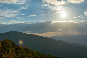 Rays of light shine down from a cloudy but blue sky onto the sides of the Blue Ridge Mountains as seen from Skyline Drive inside Shenandoah National Park, Virginia.