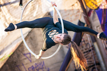 Young beautiful woman dancing on an aerial ring outside