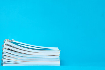 Notebooks laid on top of each other on a blue vivid background