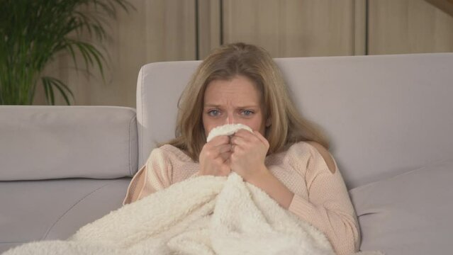 CLOSE UP: Pretty Young Woman Hiding Behind Blanket While Watching Horror Movie. Lady Sitting On A Comfy Couch And Watching Television. Female Person At Relaxing Leisure Activity For Winter Evenings.