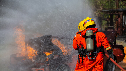 Asian firefighter on duty firefighting, Asian fireman spraying high pressure water, Fireman in fire fighting equipment uniform spray water from hose for fire fighting.