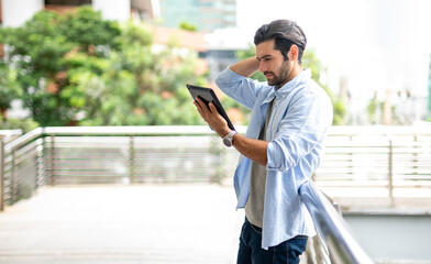 The young man using a tablet to working at out of office. The man wearing casual cloth and feeling thinking and seriously.