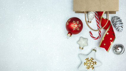 christmas ornaments and baubles fall out from a shopping paper bag. festive silver background, top...