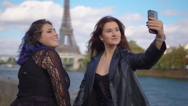 Two girls take a selfie on their phone in the most visited city in the world. Traveling together concept. A young couple takes a photo in Paris. Video phone call