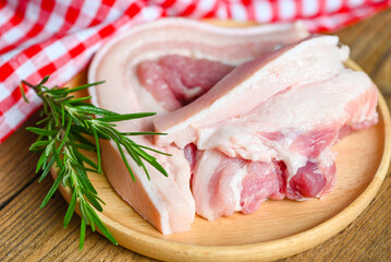 pork on wooden plate with rosemary, fresh raw streaky pork meat for cooking food, pork skin pig skin - top view
