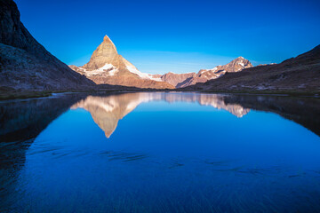 Fototapeta na wymiar Matterhorn iconic mountain and lake relfection at peaceful sunrise, Swiss Alps
