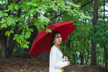 雨の公園で傘を持っている女性