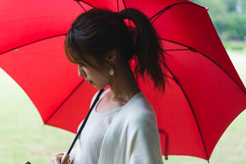 雨の公園で傘を持っている女性