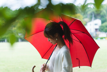 雨の公園で傘を持っている女性
