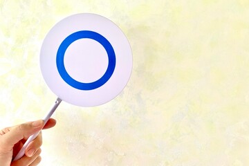 手でマルのプレートを持つ 正解を示す