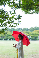 雨の公園で傘を持っている女性