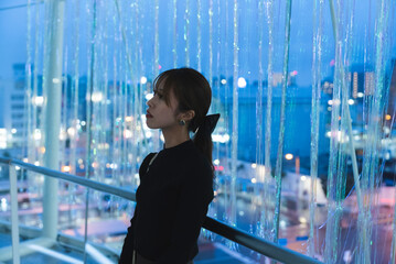 Fototapeta premium イルミネーションのあるビルの中で待ち合わせをする女性