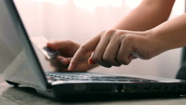 Close-up of the finger, Woman pressed the credit card code to pay online via the laptop at the desk in the hotel room, Online purchases and use of credit cards concept.