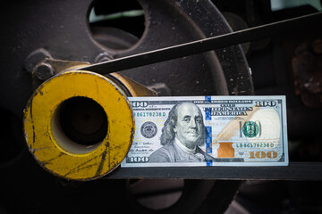 Close-up of a one hundred US dollar bill on a belt driven pulley. Belts for transmission of torque...