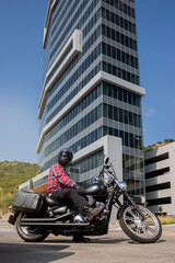 Man in a motorbike in a parking lot with a building behind