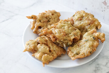 Bakwan goreng, fried food, Indonesian traditional street food snacks. fried vegetables dough fritters, appetizer on a white plate