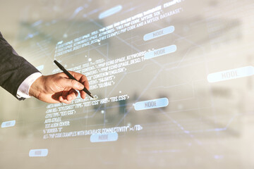 Double exposure of programmer's hand with pen working with abstract creative programming illustration on blurred office background, big data and blockchain concept