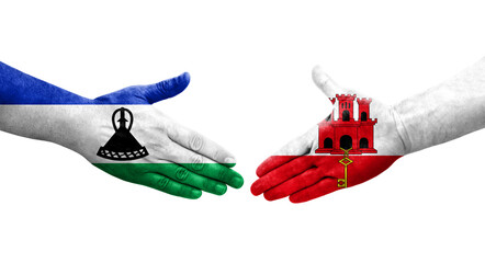 Handshake between Gibraltar and Lesotho flags painted on hands, isolated transparent image.