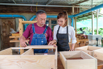 Tutor With Female Carpentry Student In Workshop Studying For Apprenticeship At College ,Teacher explaining a structure students while standing in a woodwork class