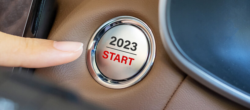 Finger press a car ignition button with 2023 START text inside  automobile. New Year New You, forecast, resolution, motivation, change, goal, vision, innovation and planning concept