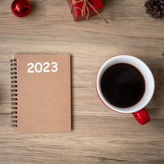 2023 notebook, black coffee cup and Christmas gift on wood table, Top view and copy space. Xmas, Happy New Year, Goals, Resolution, To do list, Strategy and Plan concept