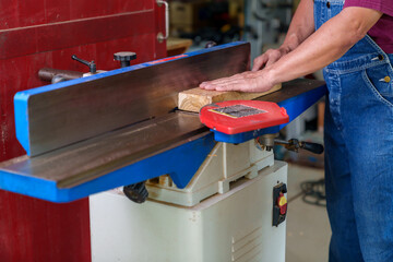 Tutor With Male Carpentry Student In Workshop Studying For Apprenticeship At College Using Bench Saw