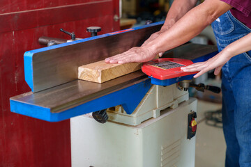 Tutor With Male Carpentry Student In Workshop Studying For Apprenticeship At College Using Bench Saw